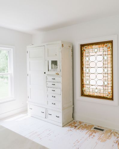 All white kitchen with a colorful, antique pink stain glass window.